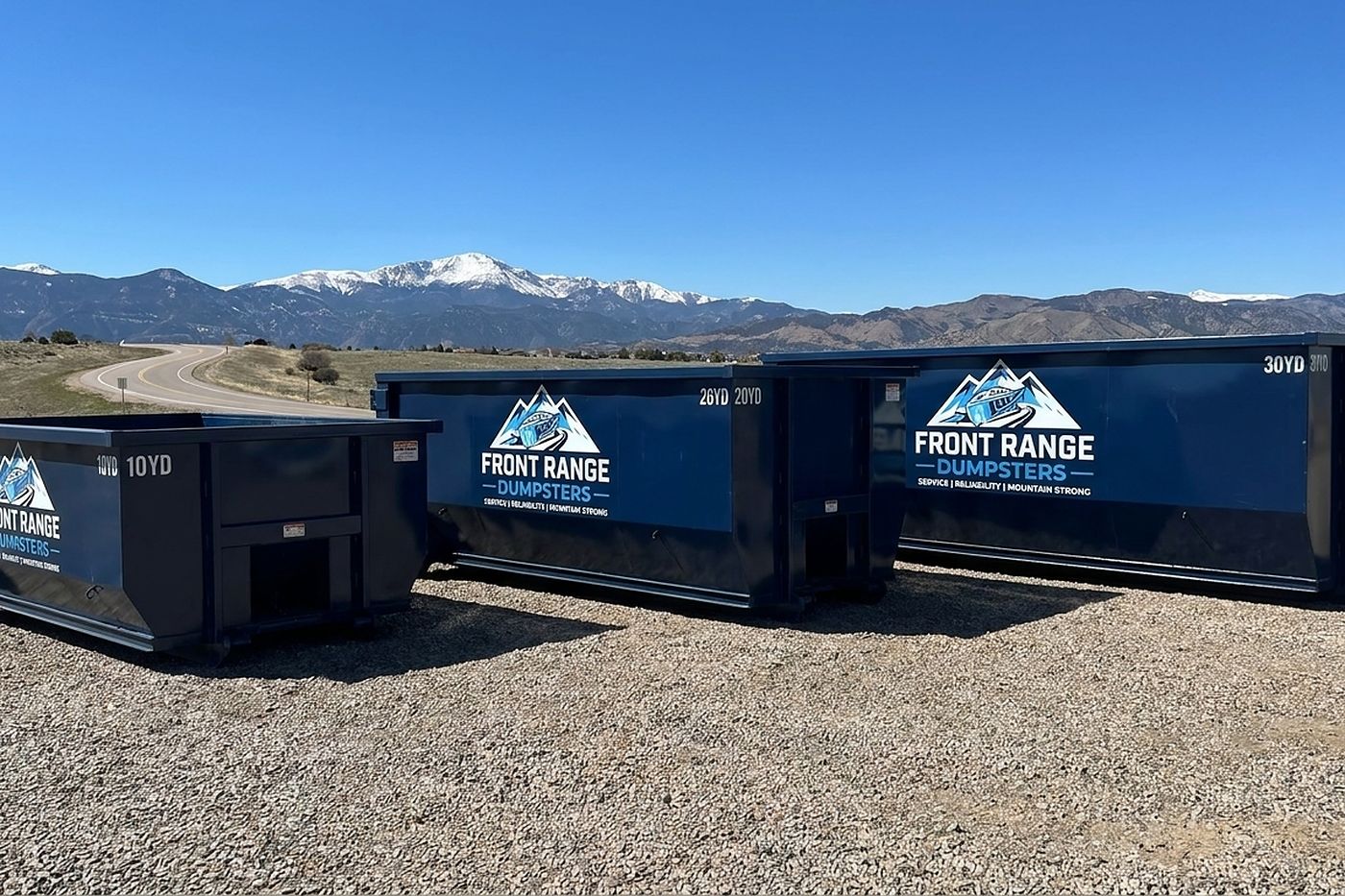 Three Front Range Dumpsters roll-off containers, 10, 20 and 30 yards, on gravel with mountains behind